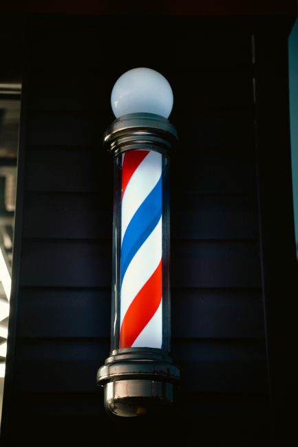 A classic barber pole lit up outside a shopfront